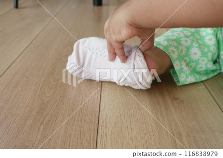 a little girl trying to take off her socks a little girl trying to take off her socks 116838979