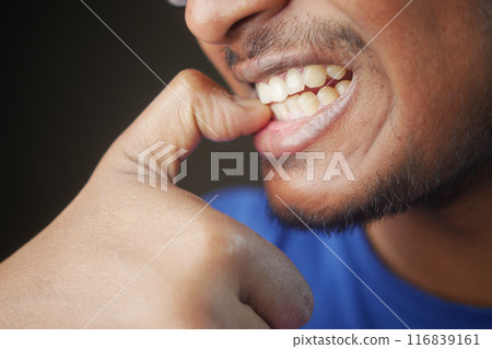 young men biting his nails at home, 116839161