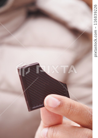 The image shows a detailed view of a hand holding a portion of rich dark chocolate The image shows a detailed view of a hand holding a portion of rich dark chocolate 116839226