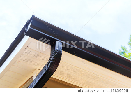 Installing rain gutters on roof installing downpipe, downspout bend 116839906