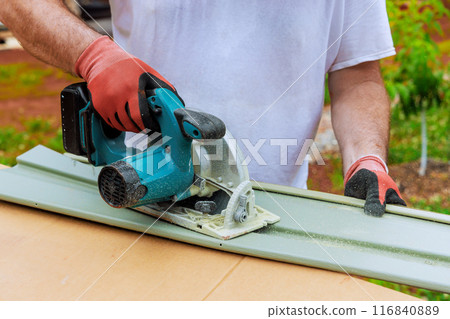 Working with circular handsaw, worker cuts plastic vinyl siding to desired size before installing it Working with circular handsaw, worker cuts plastic vinyl siding to desired size before installing it 116840889