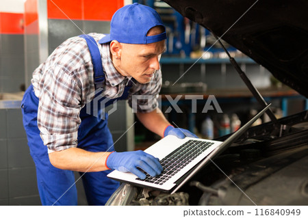 Mechanic man with laptop making car diagnostics at service Mechanic man with laptop making car diagnostics at service 116840949