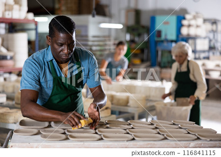 Male ceramist polishing new clay plates 116841115