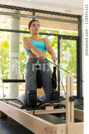 Girl pilates exercises on machines in a health club. Girl pilates exercises on machines in a health club. 116841122