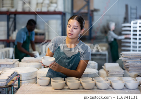 Young woman foreman checks the quality of pottery in the workshop for production of clay products 116841131