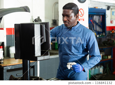 Mechanic balancing tire in auto repair shop using computer 116841132