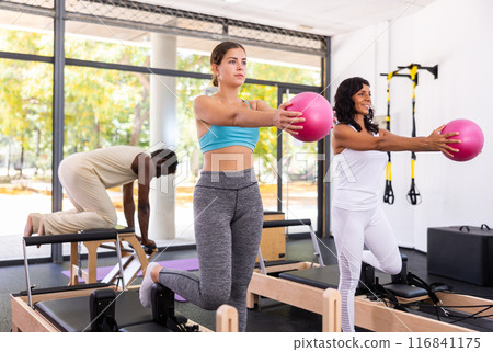 Man and woman exercising with ball at pilates lesson Man and woman exercising with ball at pilates lesson 116841175