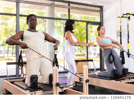 Active middle-aged African American man and young Woman doing pilates exercises Active middle-aged African American man and young Woman doing pilates exercises 116841179