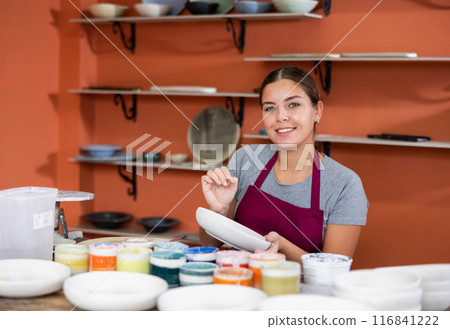 Positive woman painting plate with brush Positive woman painting plate with brush 116841222