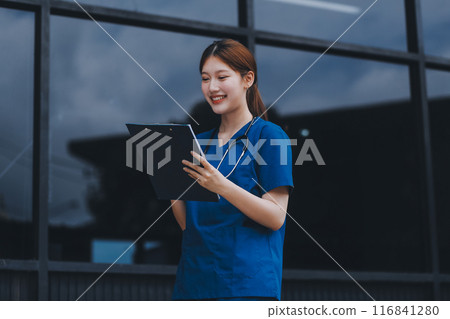 Confident nurse on her way to work in a clinic. Pretty female nurse drinking coffee and rest after hard work. The young adult female nurse drinks her coffee as she arrives to work at the hospital. 116841280