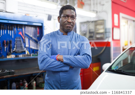 Portrait of confident mechanician posing near car at service 116841337