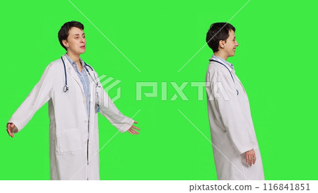 Friendly medic waving hello and greeting patients against greenscreen backdrop, smiling before her exam appointments. Woman physician with white coat welcoming people and being happy. Camera B. Friendly medic waving hello and greeting patients against greenscreen backdrop, smiling before her exam appointments. Woman physician with white coat welcoming people and being happy. Camera B. 116841851
