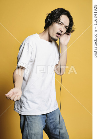 Man listening to music on a color background 116841929