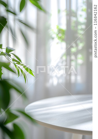 Picture a tranquil and stylish environment with a white circular table, gentle sunlight filtering through sheer drapes, and lush plants creating a serene and natural atmosphere 116842162