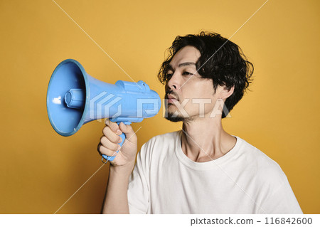 A man shouting into a megaphone against a colored background A man shouting into a megaphone against a colored background 116842600