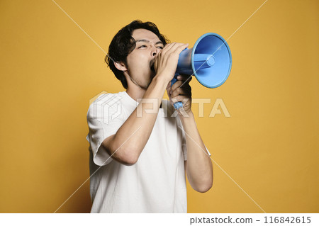 A man shouting into a megaphone against a colored background 116842615