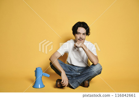 A man sitting with a loudspeaker on a colored background A man sitting with a loudspeaker on a colored background 116842661