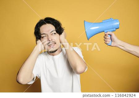 一個男人摀住耳朵,聽不到彩色背景的揚聲器的聲音 一個男人摀住耳朵,聽不到彩色背景的揚聲器的聲音 116842924