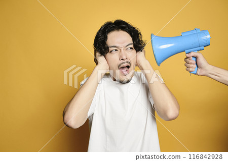 一個男人摀住耳朵,聽不到彩色背景的揚聲器的聲音 一個男人摀住耳朵,聽不到彩色背景的揚聲器的聲音 116842928