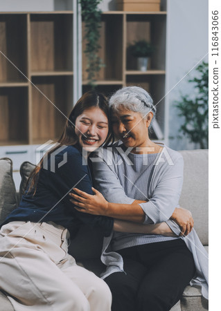 Adult daughter old mom hugging sit on couch enjoy pleasant positive talk, remembering funny occasion from life spend weekend together, caring about older generation relatives express attention concept 116843066