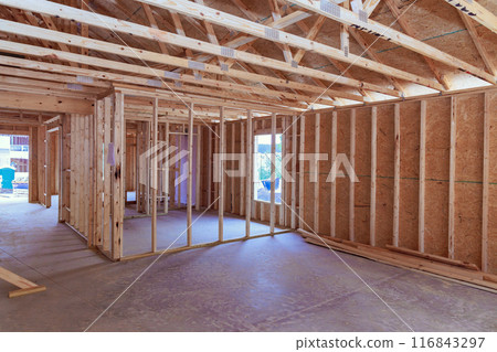 Framing of new unfinished residential home under construction is made up wood supports beam Framing of new unfinished residential home under construction is made up wood supports beam 116843297