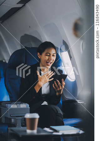 Business woman uses mobile phone and laptop to chat with friends sitting in airplane. Business woman uses mobile phone and laptop to chat with friends sitting in airplane. 116843490