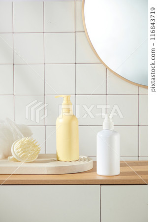 Photograph of bathroom concept was taken from frontal on white checkered brick wall background. Two bottle of shower gel or shampoo without label displayed on top of wooden cabinet 116843719
