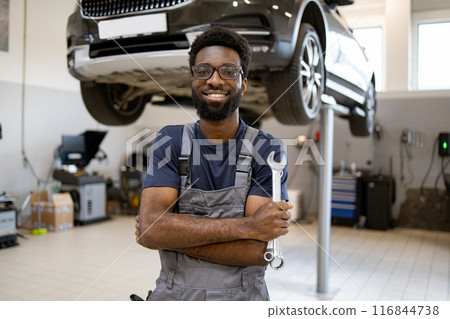 Confident mechanic holding wrench in car repair shop 116844738