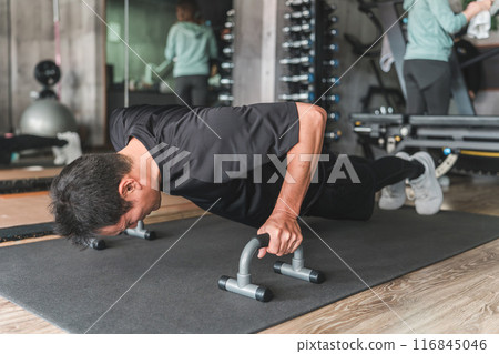 A man doing push-ups using a push-up bar at the gym 116845046