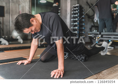 一名男子在健身房使用泡沫軸來放鬆大腿的肌筋膜。 一名男子在健身房使用泡沫軸來放鬆大腿的肌筋膜。 116845054