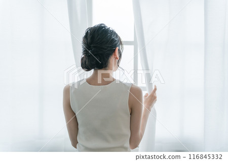 A woman basking in the morning sun in front of the curtains when she wakes up A woman basking in the morning sun in front of the curtains when she wakes up 116845332