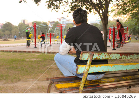 A picture of young boy sitting on chair with facing away from the camera 116846269