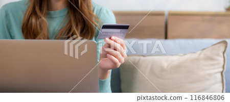 Young asian woman sitting on sofa using laptop computer shopping online with credit card. 116846806