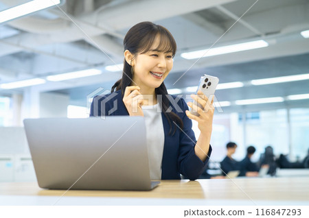 A young woman operating a smartphone in the office A young woman operating a smartphone in the office 116847293