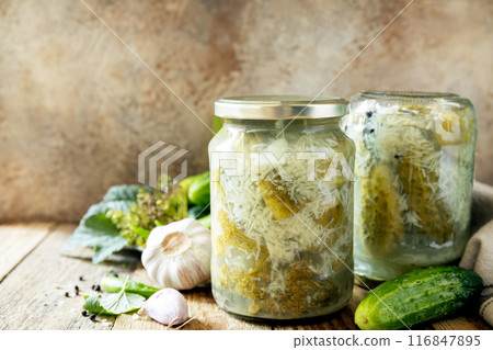 Healthy homemade fermented food. Salted pickled cucumbers with garlic, preserved canned in glass jar. Home economics, autumn harvest preservation. Copy space. 116847895