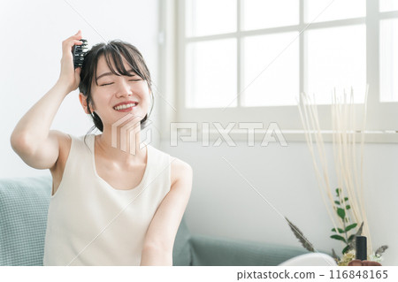 A woman doing head massage and scalp care with a scalp brushing, shampoo brush, and head brush in the room 116848165