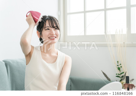 A woman doing head massage and scalp care with a scalp brushing, shampoo brush, and head brush in the room 116848166