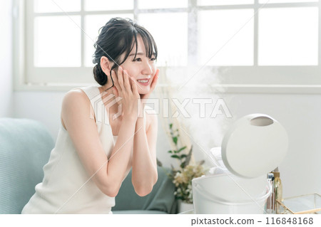 A woman who does face care, skin care, and deep cleansing with a facial steamer/facial device 116848168