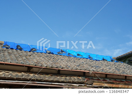 A blue tarp was placed on the roof to prevent leaks. A blue tarp was placed on the roof to prevent leaks. 116848347