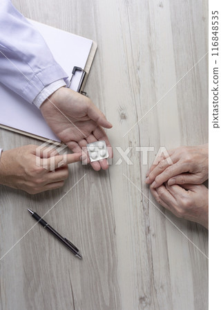 A doctor or pharmacist explaining medication to an elderly person 116848535