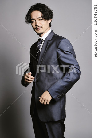 A man in a suit standing against a grey background A man in a suit standing against a grey background 116848781
