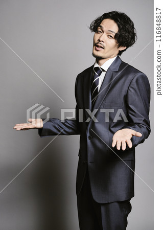 A man in a suit standing against a grey background A man in a suit standing against a grey background 116848817