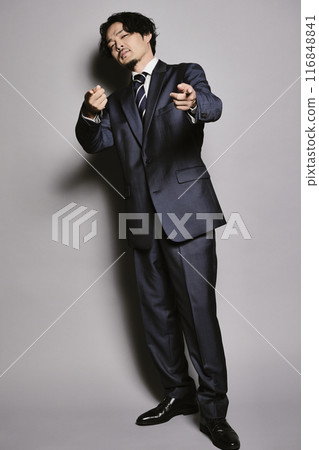 A man in a suit standing against a grey background 116848841