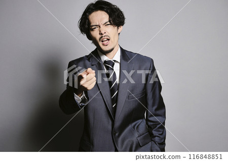 A man in a suit standing against a grey background A man in a suit standing against a grey background 116848851
