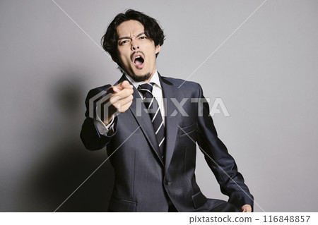 一個穿著西裝的男人站在灰色的背景下 116848857