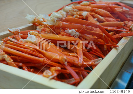 Boiled crab legs in a wooden box on a wooden table. 116849149