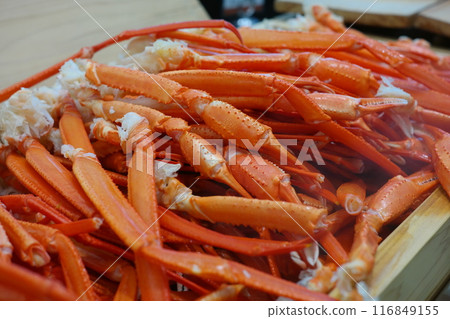 Boiled crab legs in a wooden box on a wooden table. 116849155