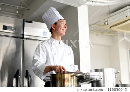 Young asian male chef preparing food in the kitchen Young asian male chef preparing food in the kitchen 116850045