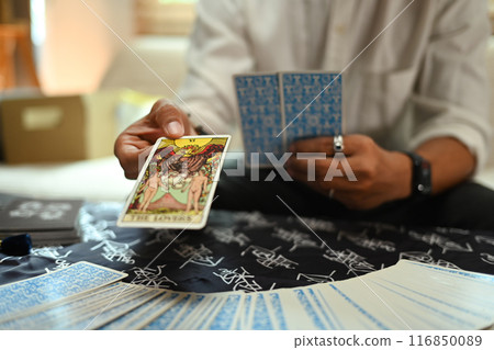 Fortune teller holding The Lovers tarot card during a reading session. Concept of witchcraft and divination 116850089