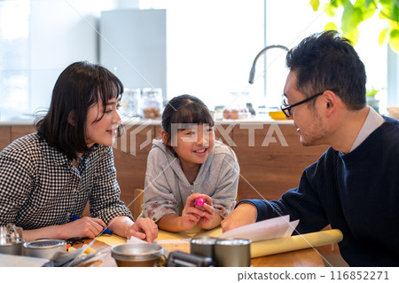 A daughter and her mother look on with amusement as their father leads a family discussion about disaster prevention. 116852271